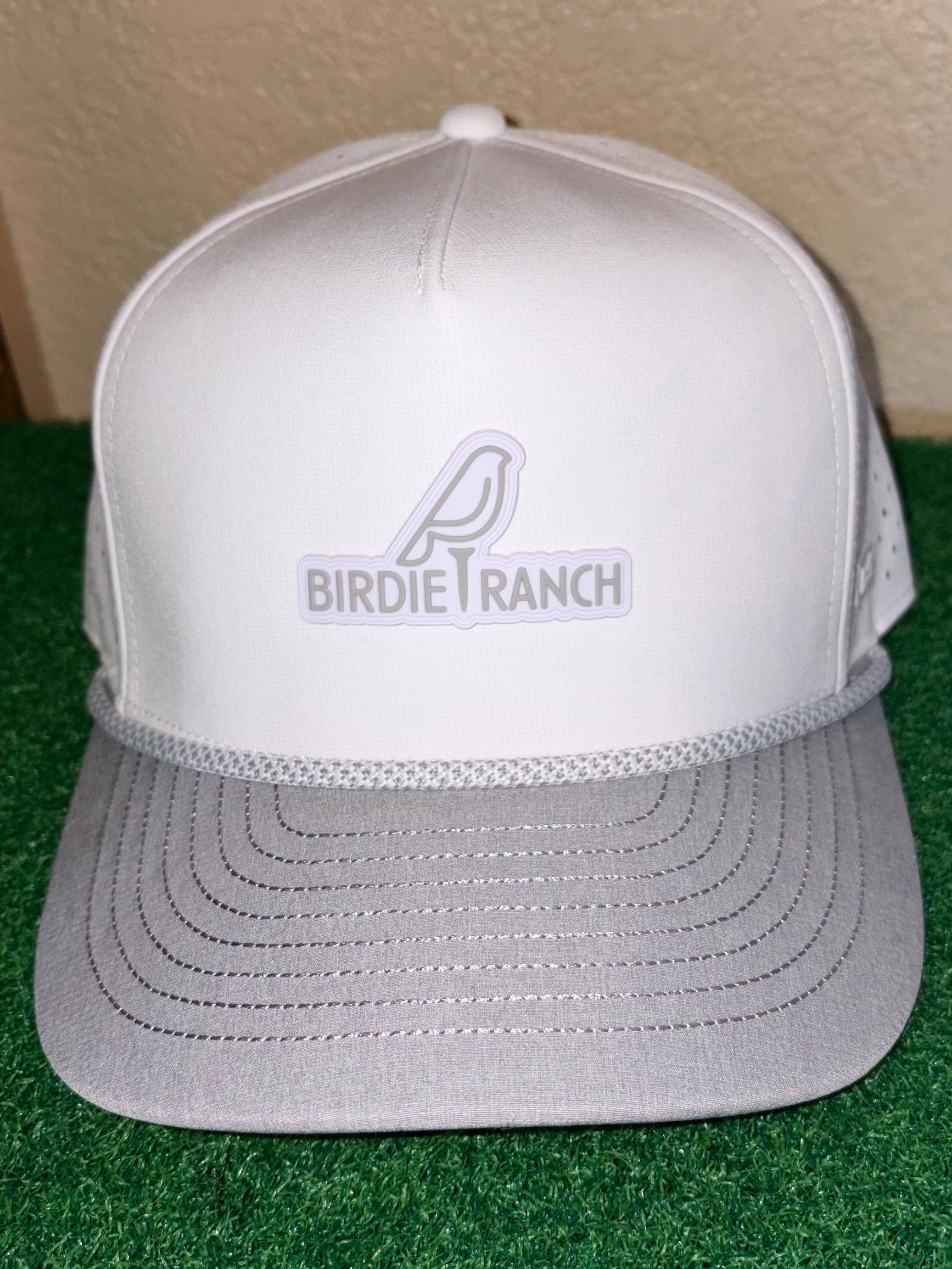White cap with 'Birdie Ranch' logo on a green surface
