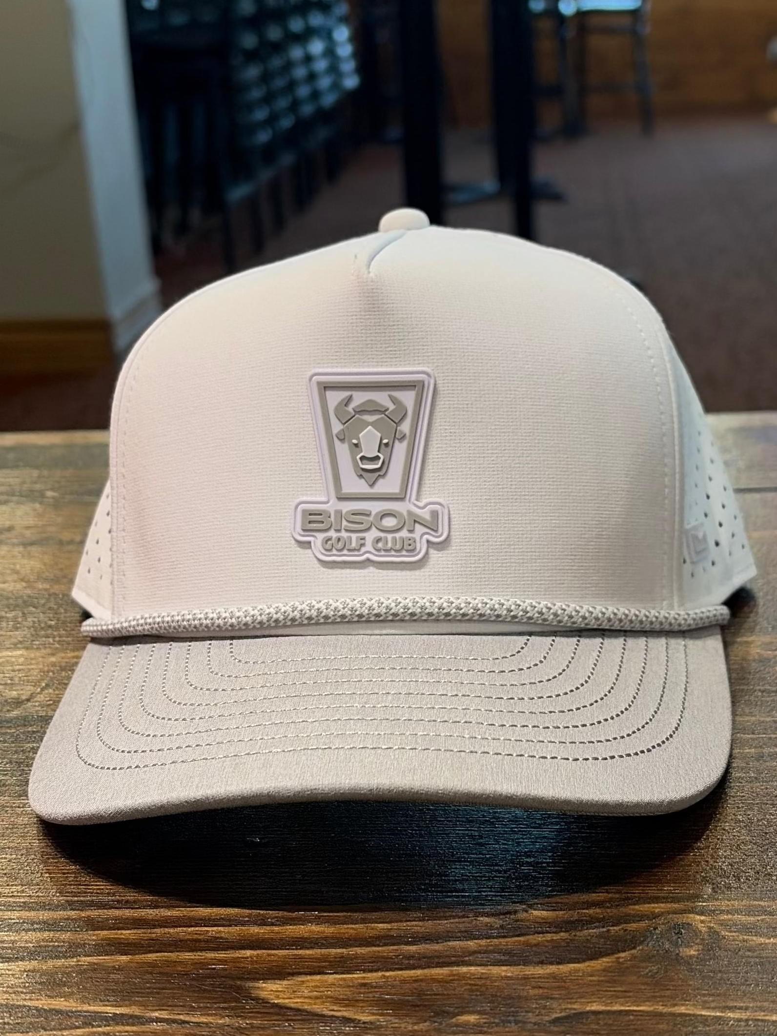 Beige cap with a logo on a wooden table inside a building