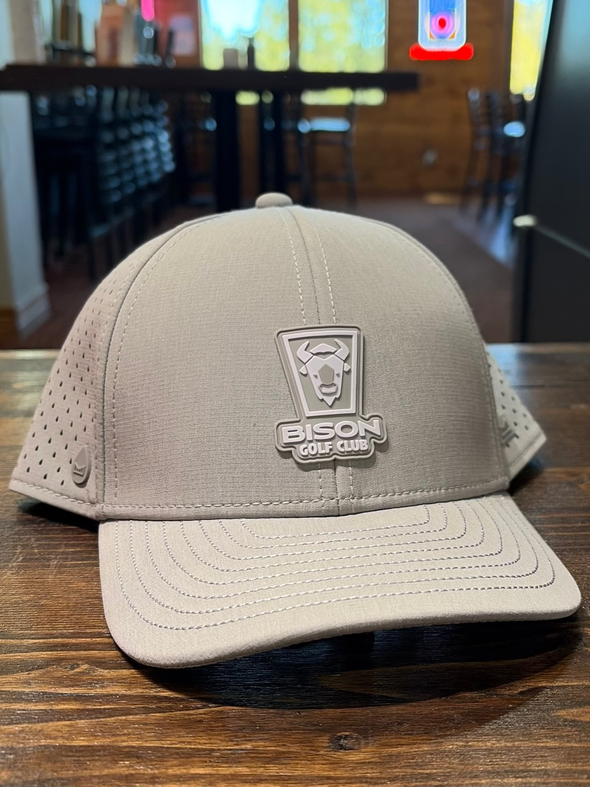 Beige cap with a logo on a wooden table in an indoor setting