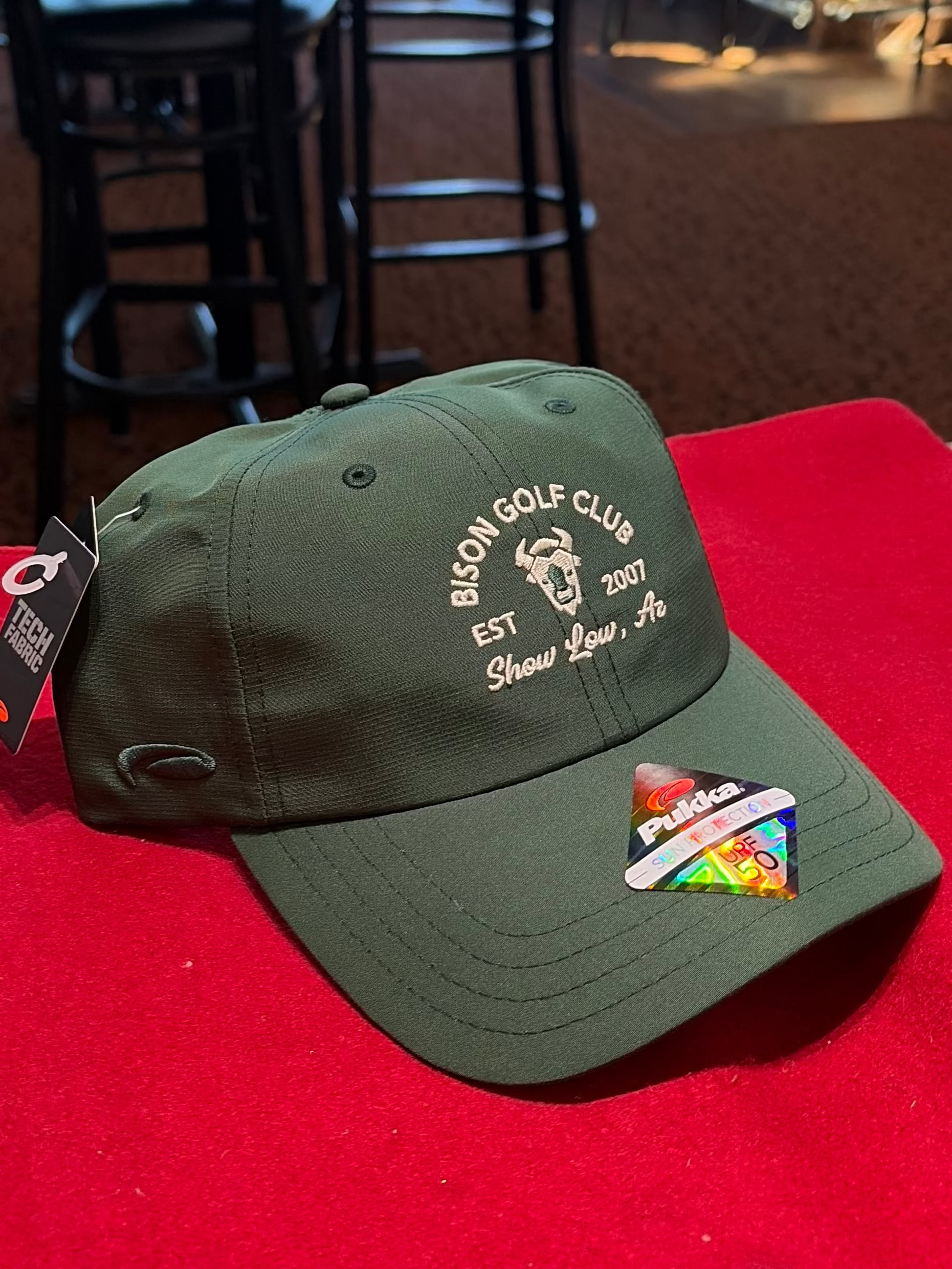 Dark Green cap with branding on a red surface